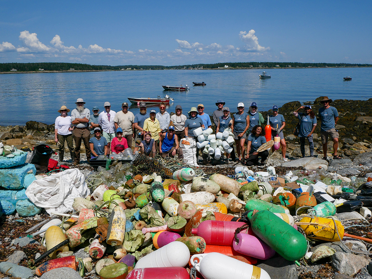 Group photo of staff and volunteers with debris removed from Hart Island. Photo credit: Rozalia Project